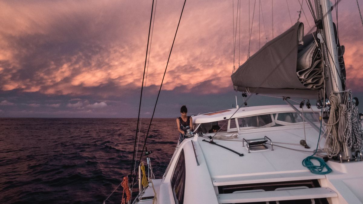 nikki wynn working the sails aboard sailing vessel curiosity at sunset in the south pacific